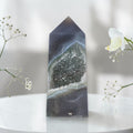 Geometric crystal on a white surface with flowers in the background