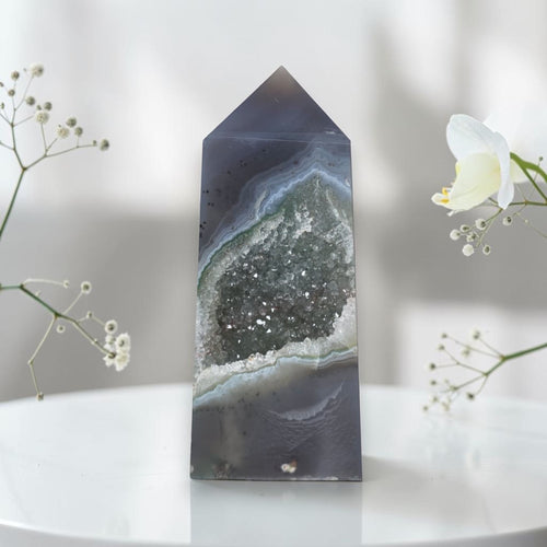 Geometric crystal on a white surface with flowers in the background