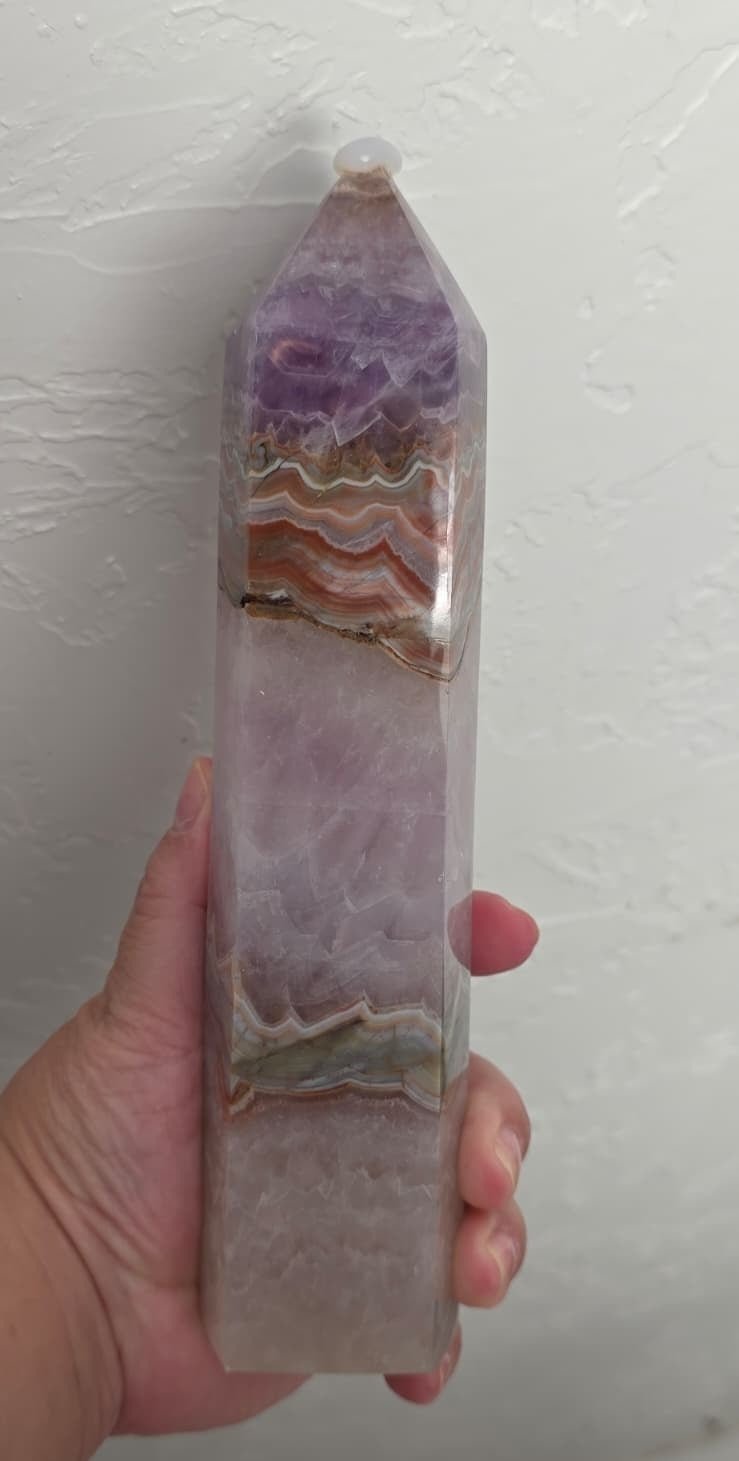 Gemstone tower in hand, amethyst purple with wavy tan lace bands