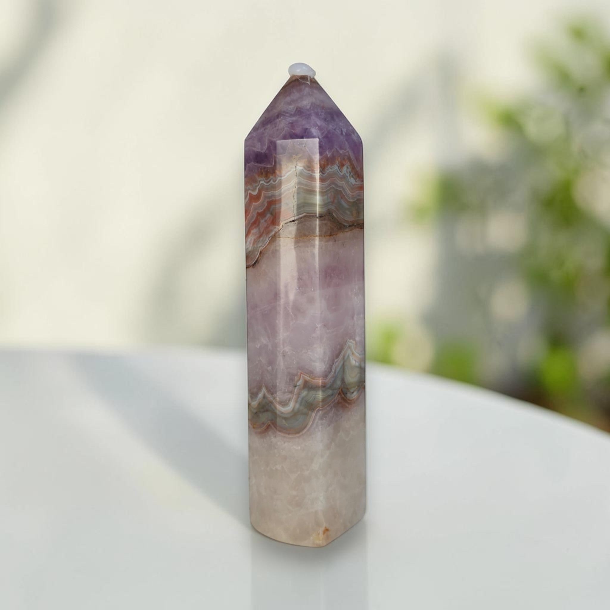 Amethyst-lavender gemstone tower with layered tan bands and faceted top