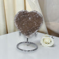 Heart-shaped crystal on a stand with a white rose on a white surface