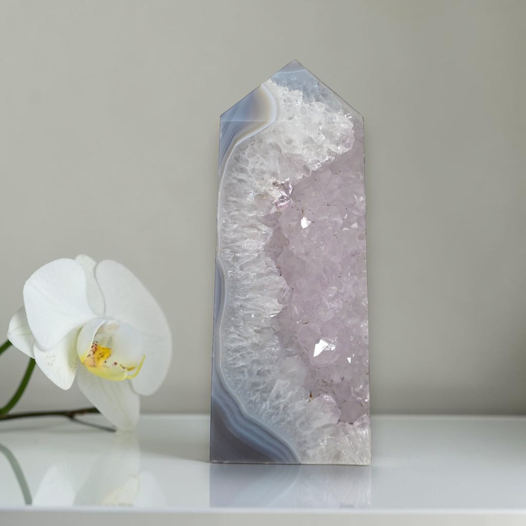 Decorative crystal tower with a white orchid on a neutral background