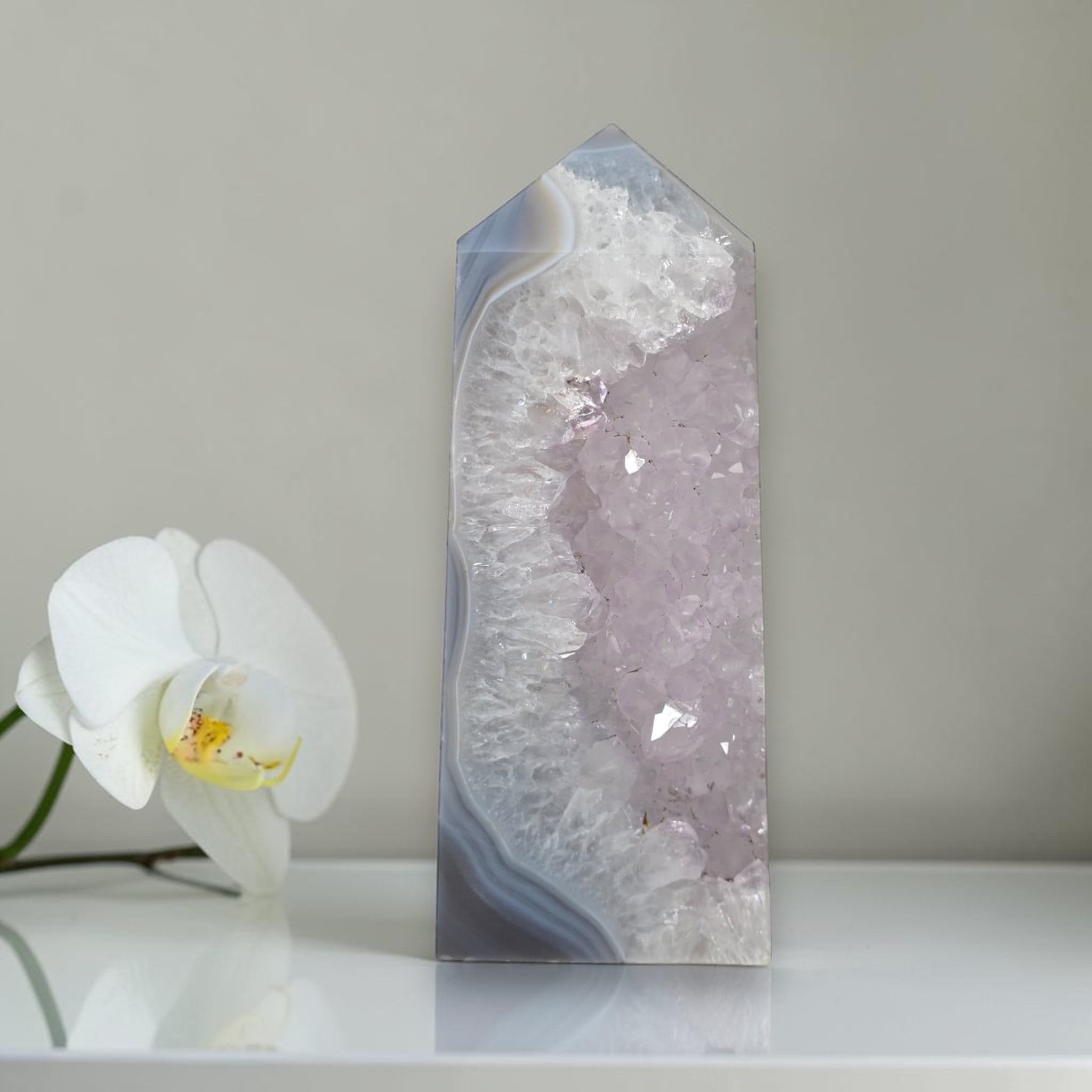 Decorative crystal tower with a white orchid on a neutral background
