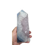 Crystal tower held in a hand against a white background