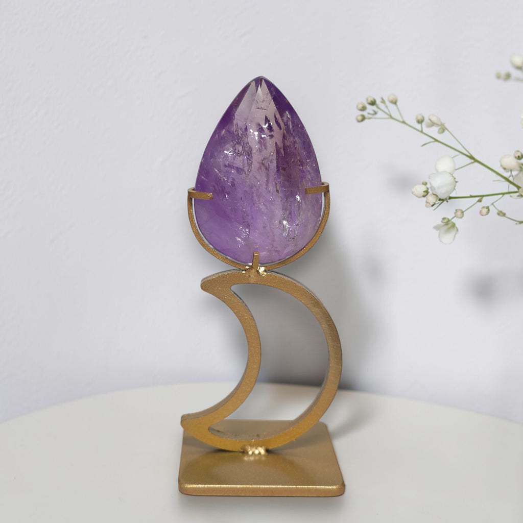 Purple amethyst teardrop mounted on gold tone crescent moon stand, front view