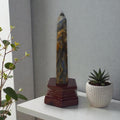 Slim blue kyanite obelisk crystal with dark red wooden stand base