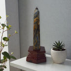 Slim blue kyanite obelisk crystal with dark red wooden stand base