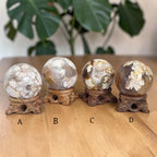 Set of four drusy gemstone spheres on carved wooden stands, white and gold crystal clusters