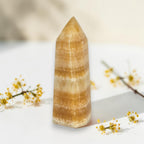 Honey-yellow calcite tower mineral point with translucent banded layers and polished tip.
