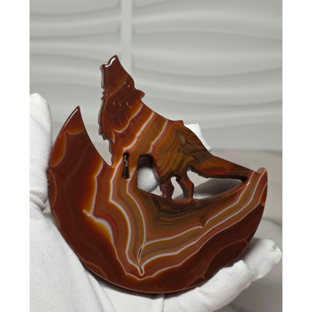 Banded agate wolf moon sculpture held in hand showing size