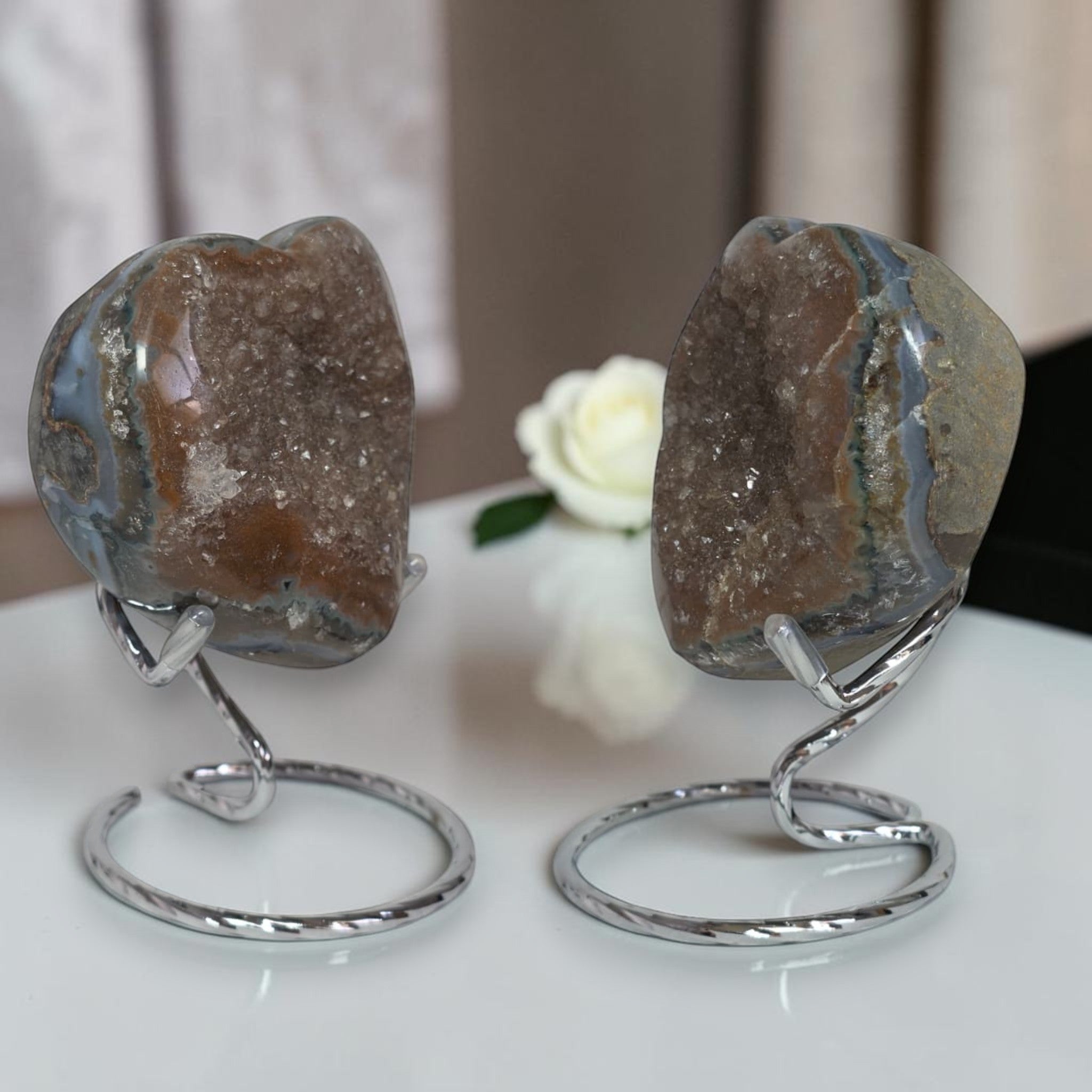 Two crystal stones on metal stands with a white flower in the background