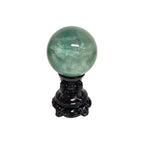 Green fluorite sphere on dark decorative stand, translucent green tone