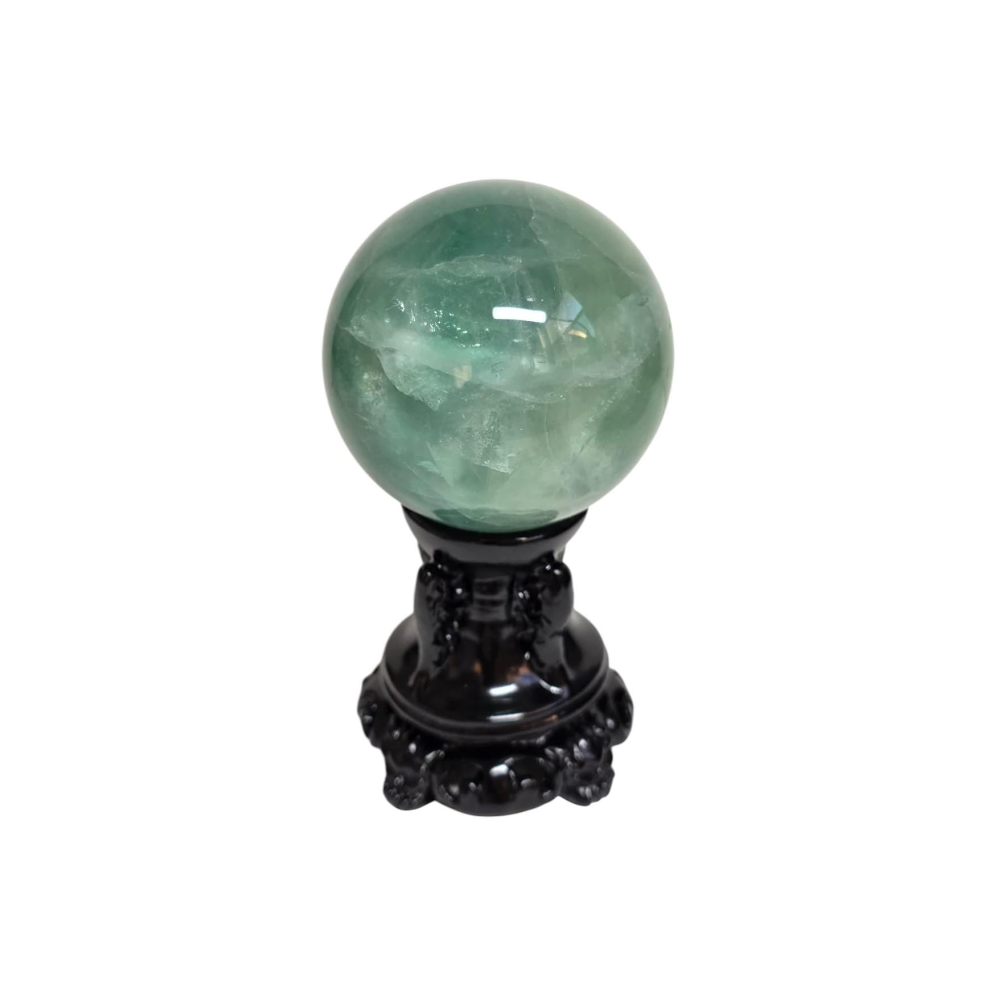 Green fluorite sphere on dark decorative stand, translucent green tone