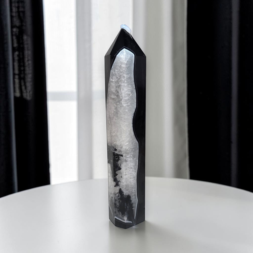 Angled view of black agate quartz crystal tower highlighting the contrast between the glossy black exterior and the sparkling white quartz interior