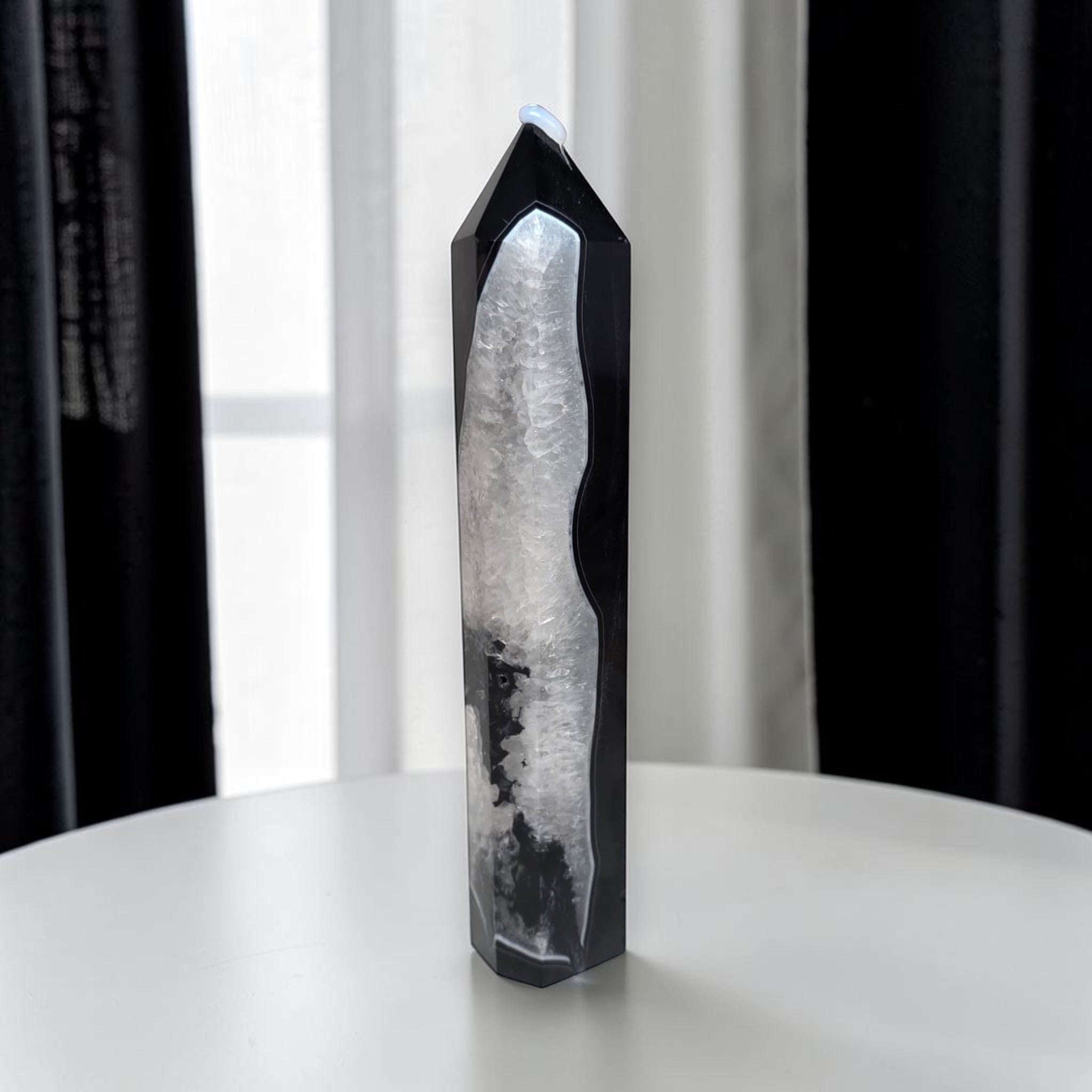 Angled view of black agate quartz crystal tower highlighting the contrast between the glossy black exterior and the sparkling white quartz interior