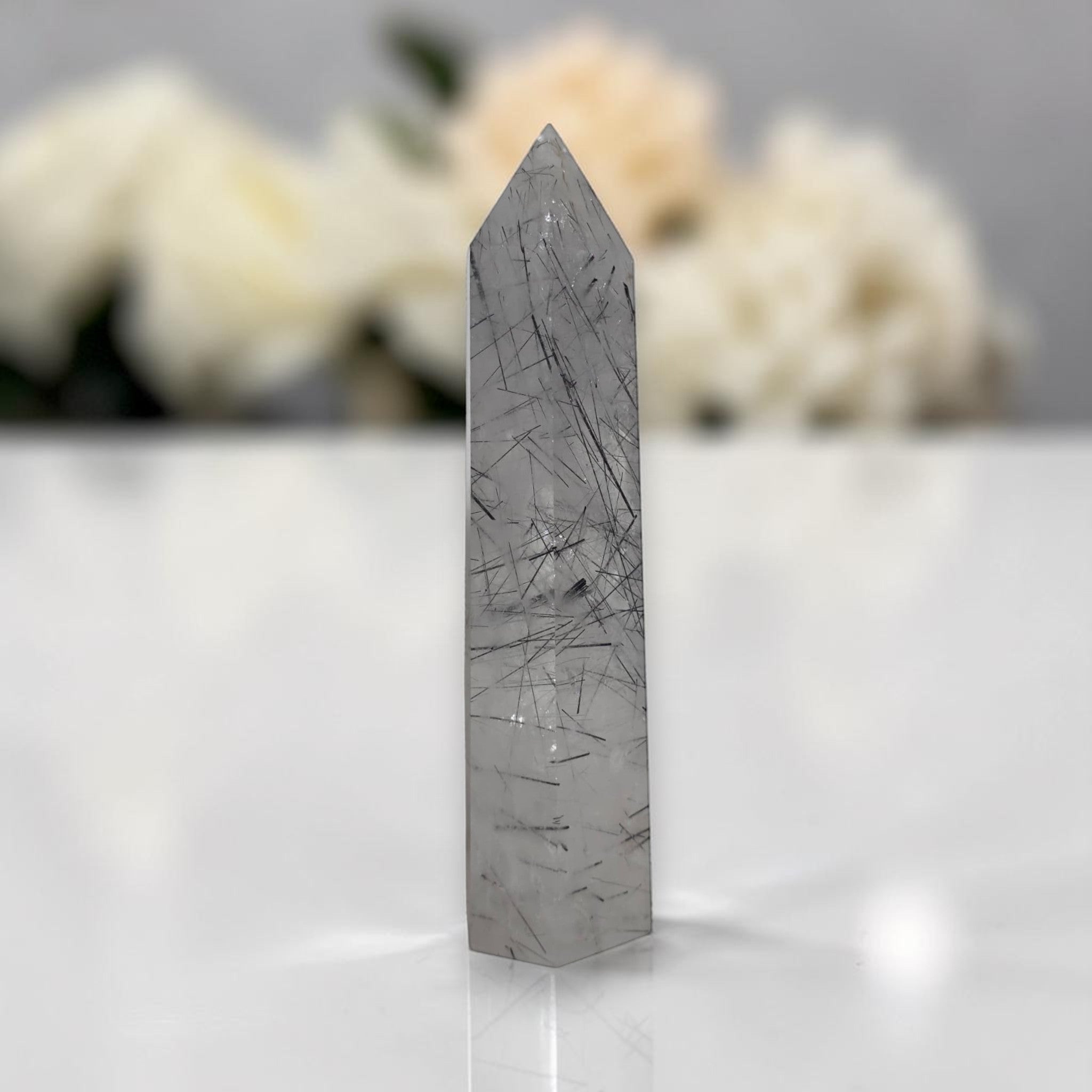 Gray rutilated quartz crystal tower with scattered dark needle-like inclusions