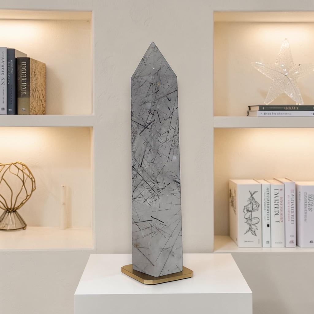 Gray rutilated quartz tower obelisk with dark needle inclusions on a display base