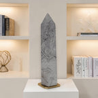 Gray rutilated quartz tower obelisk with dark needle inclusions on a display base