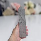 Handheld gray rutilated quartz tower with dark needle inclusions and pointed tip