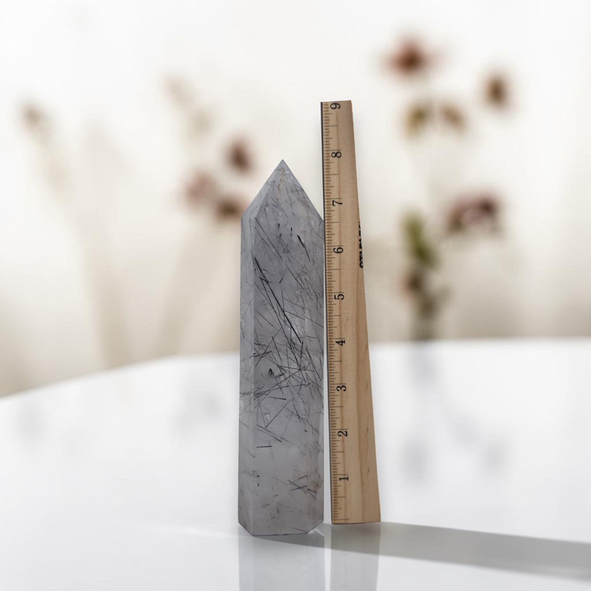 Rutilated quartz obelisk tower, gray with dark needle rutiles; measured against ruler