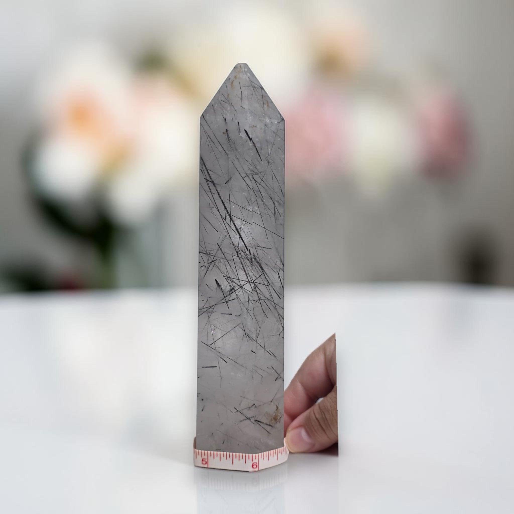 Gray rutilated quartz crystal tower with dark needle-like inclusions and pointed top