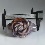 Rose-shaped agate carving next to a ruler showing size; gray-blue petals with orange-brown