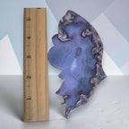 Blue agate butterfly wing sculpture beside wooden ruler, gold-tone stem and base