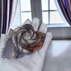 Rose-shaped agate carving on light fabric with dark petals, pale insets, and rust accents