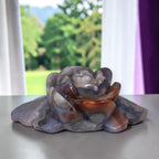 Rose-shaped agate carving with layered petals in smoky gray-blue and orange-brown stripes