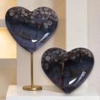 Two heart-shaped decorative items on a stand with a neutral background