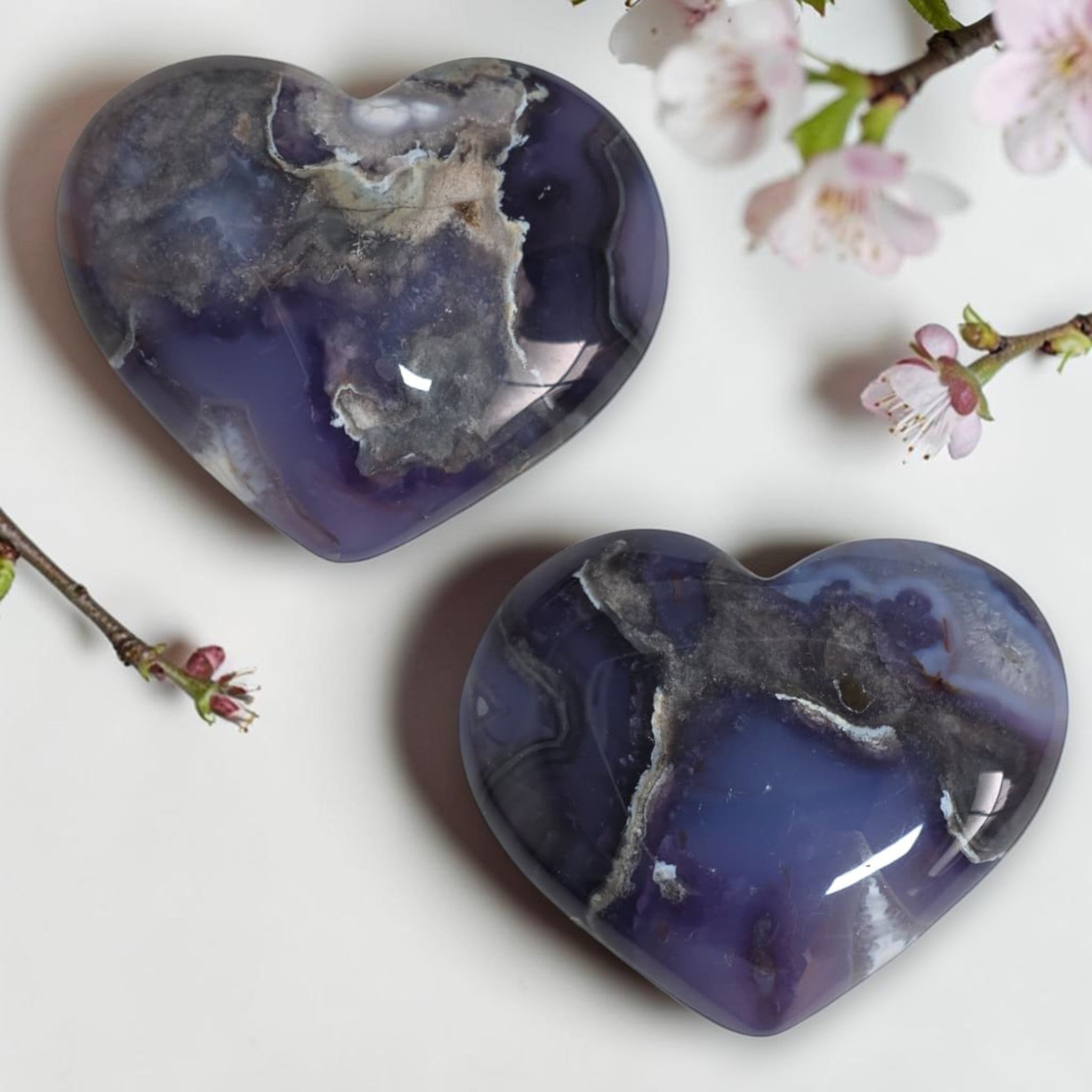Two polished dark blue agate hearts with cloudy white inclusions and glossy shine