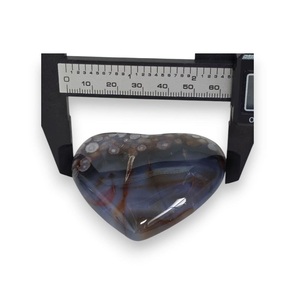 Heart-shaped agate stone with a ruler for scale on a white background