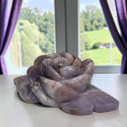 Rose-shaped agate carving with curled petals in muted gray, lavender, and amber bands