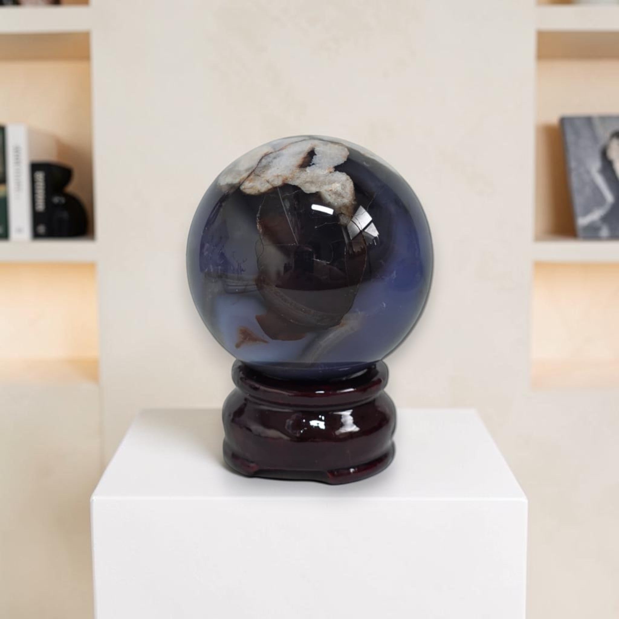 Blue crystal ball on a wooden stand against a blurred bookshelf background