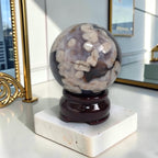 Decorative crystal sphere on a stand with a marble base in a room setting.