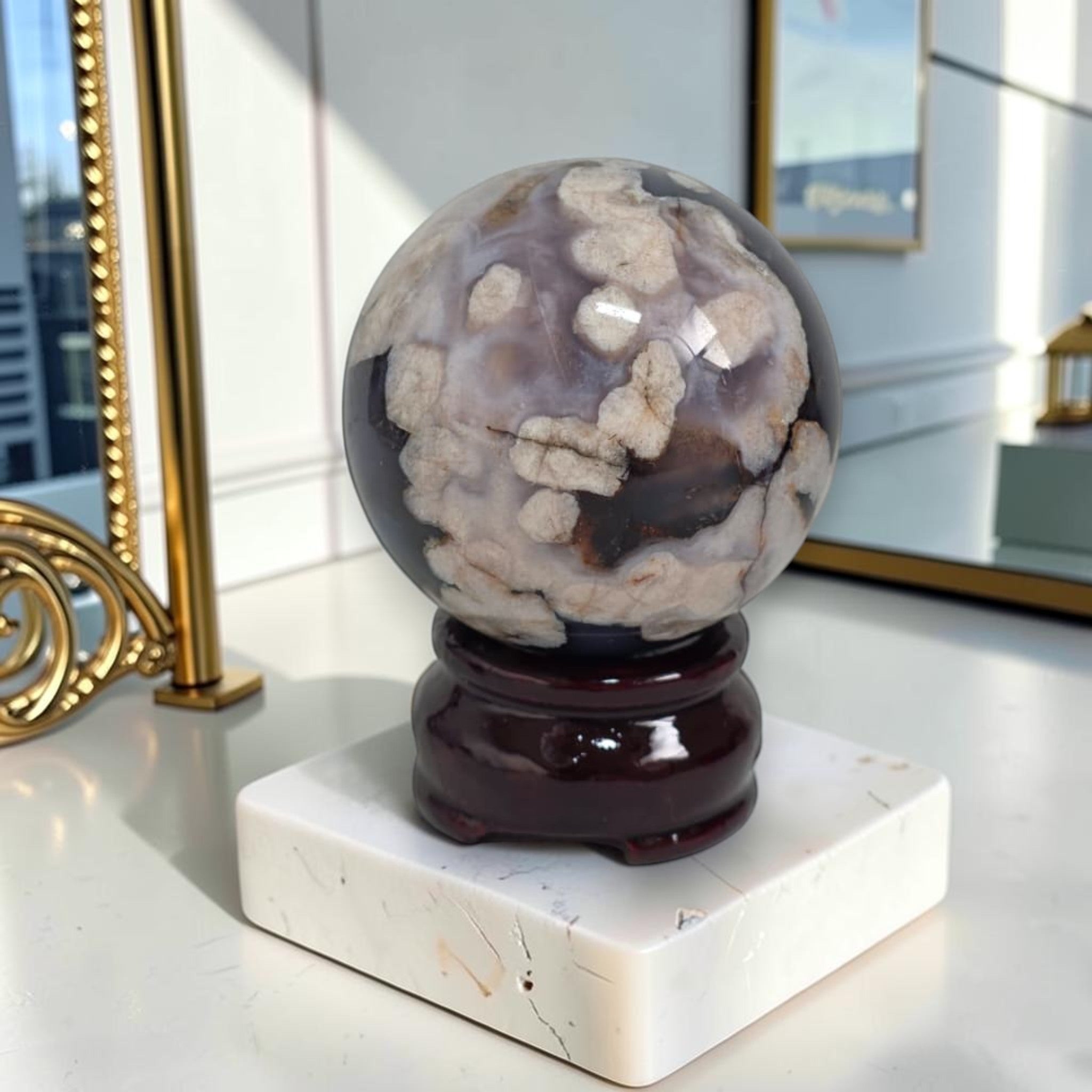 Decorative crystal sphere on a stand with a marble base in a room setting.