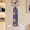 Decorative vase with floral design on a white pedestal against a neutral wall.