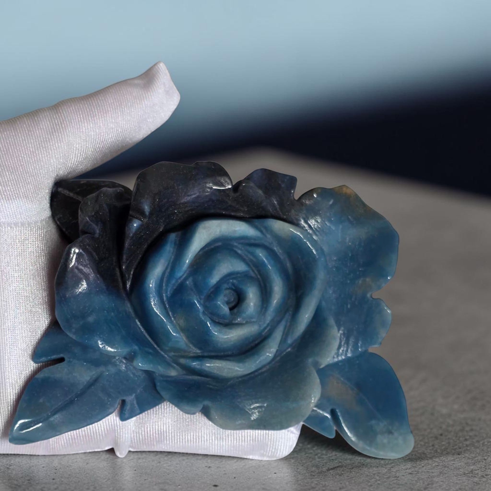 Close-up of natural Trolleite rose carving showing deep blue and indigo color variation and hand-carved petal detail