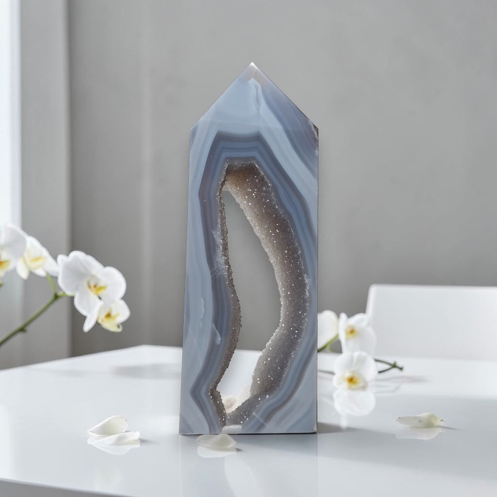 Geometric crystal sculpture on a white surface with white flowers