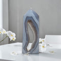 Geometric crystal sculpture on a white surface with white flowers
