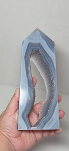 Geode crystal held in a hand against a plain background