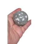 Light gray jasper crystal ball sphere in hand, speckled stone texture