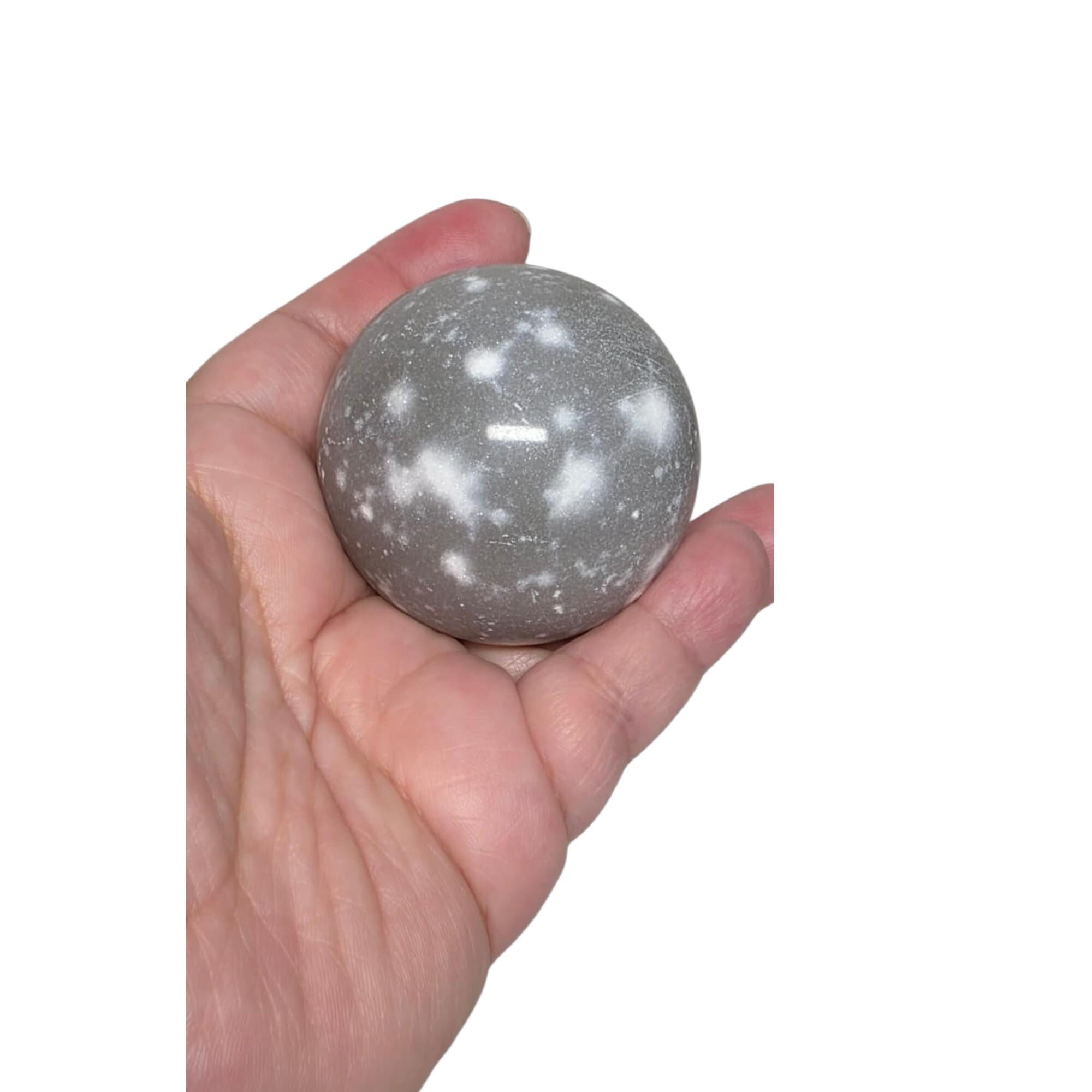 Light gray jasper crystal ball sphere in hand, speckled stone texture