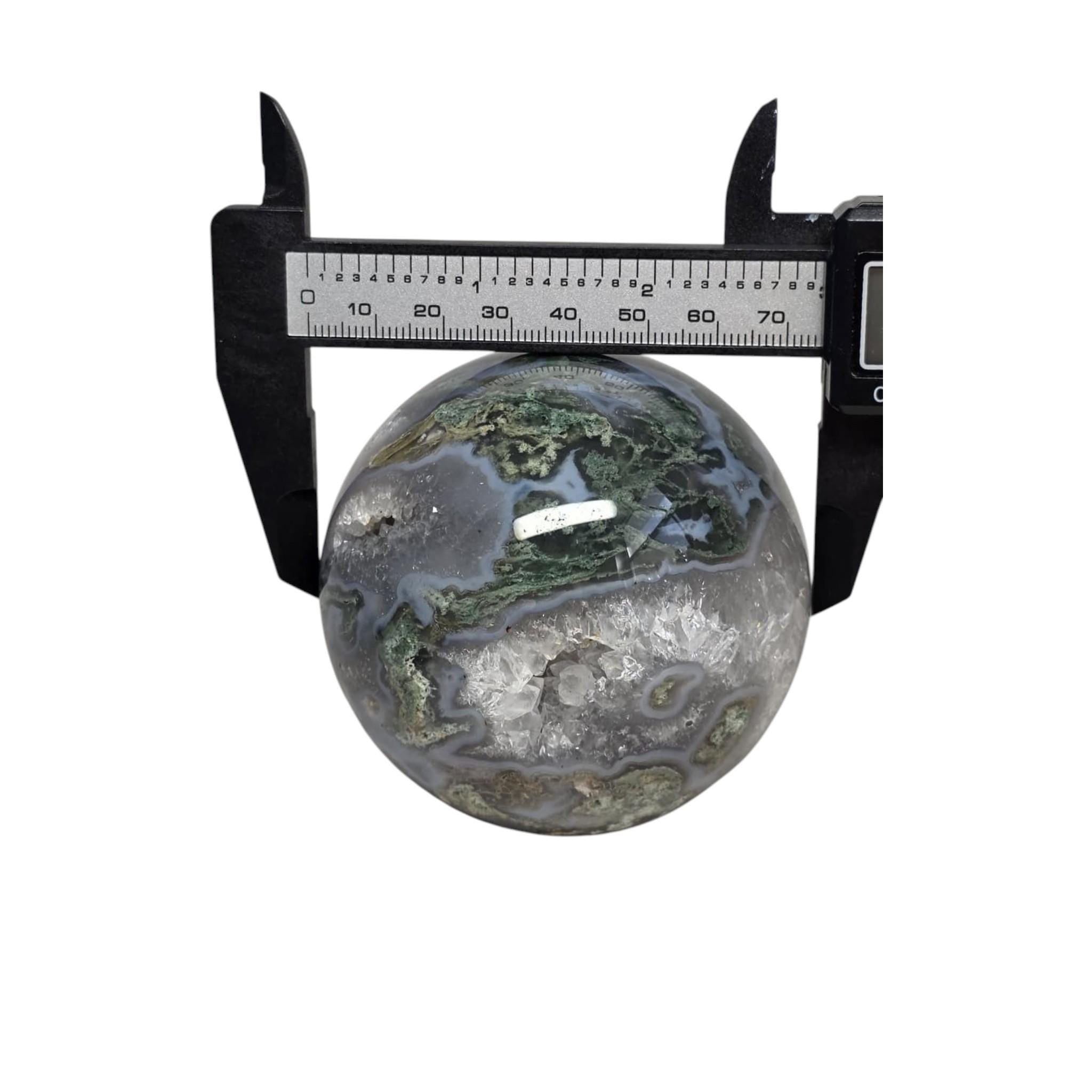 Moss agate geode sphere measured with calipers; dark gray-blue with green mossy inclusions