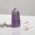 Amethyst quartz point tower, violet crystal with clear facets and flat base.