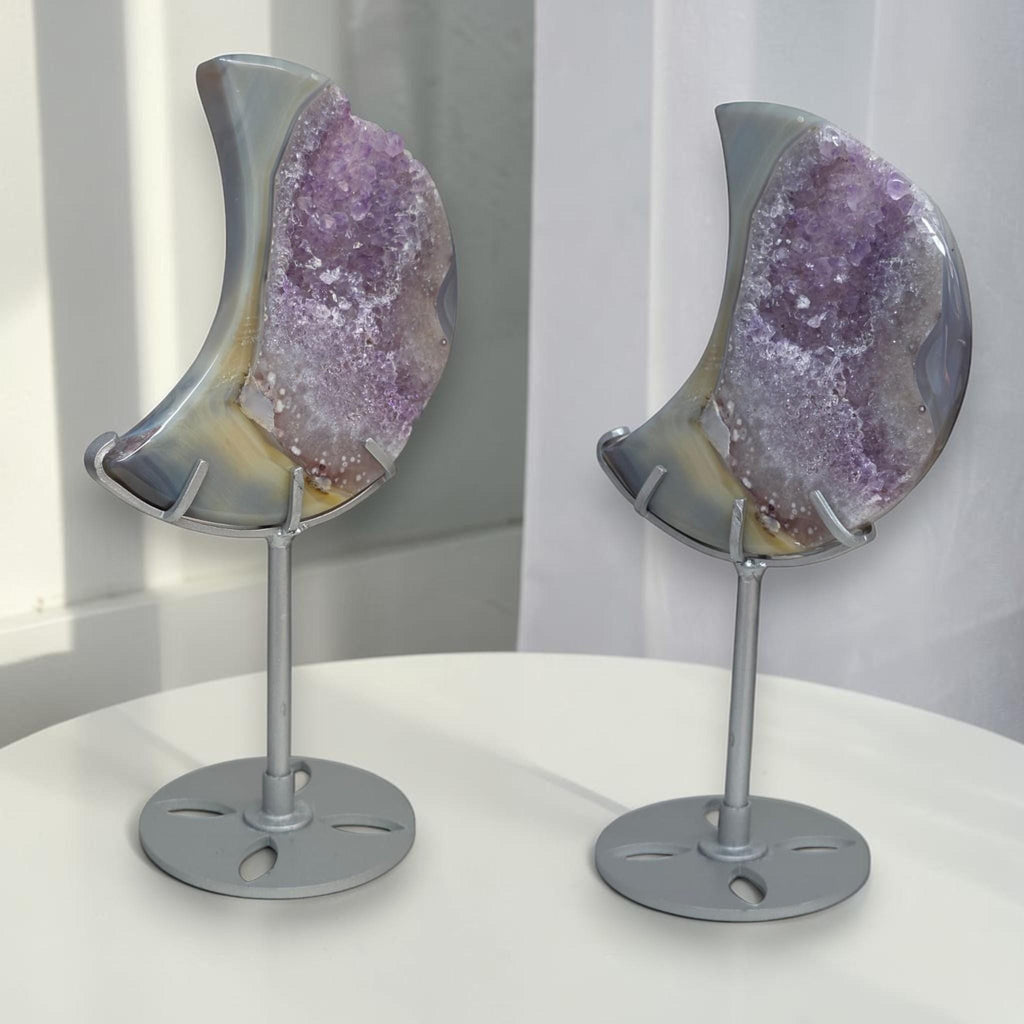 Pair of crescent moon purple druzy agate geodes on silver stands, angled view