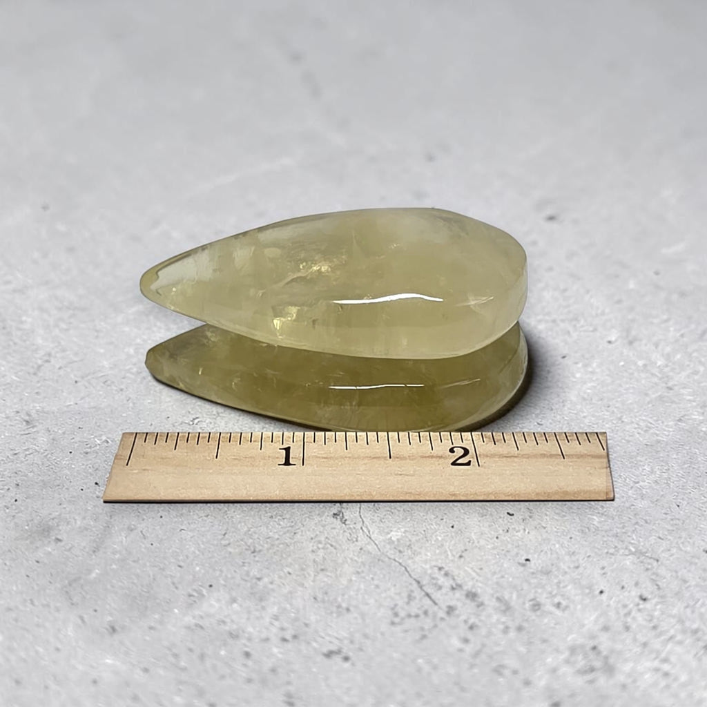 Two yellow crystal slabs with smooth edges, shown with a 1–2 in ruler