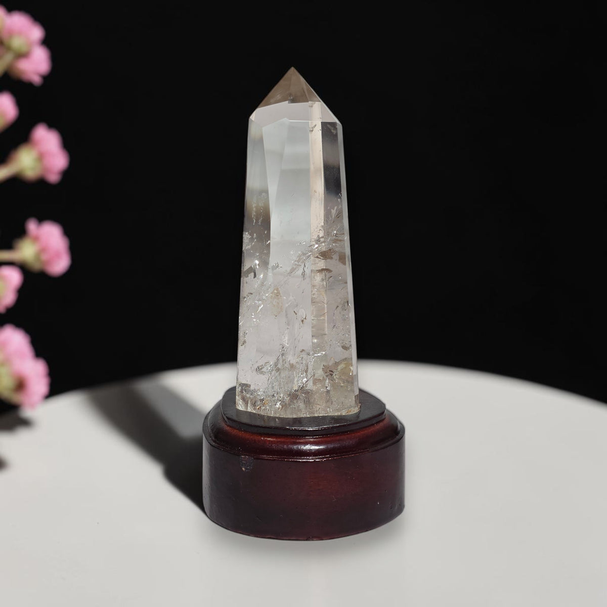Polished clear quartz obelisk tower on display stand