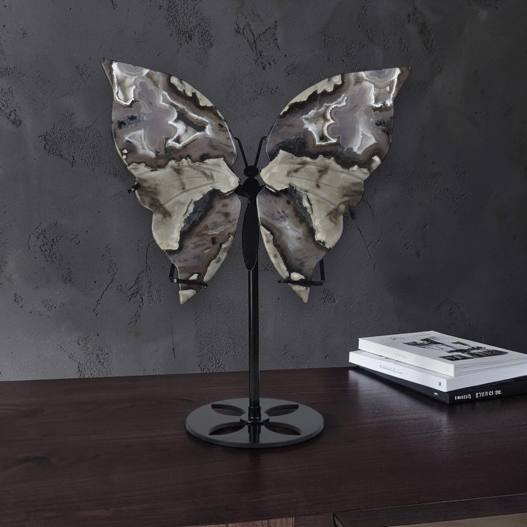 Decorative butterfly sculpture on a stand against a dark wall.