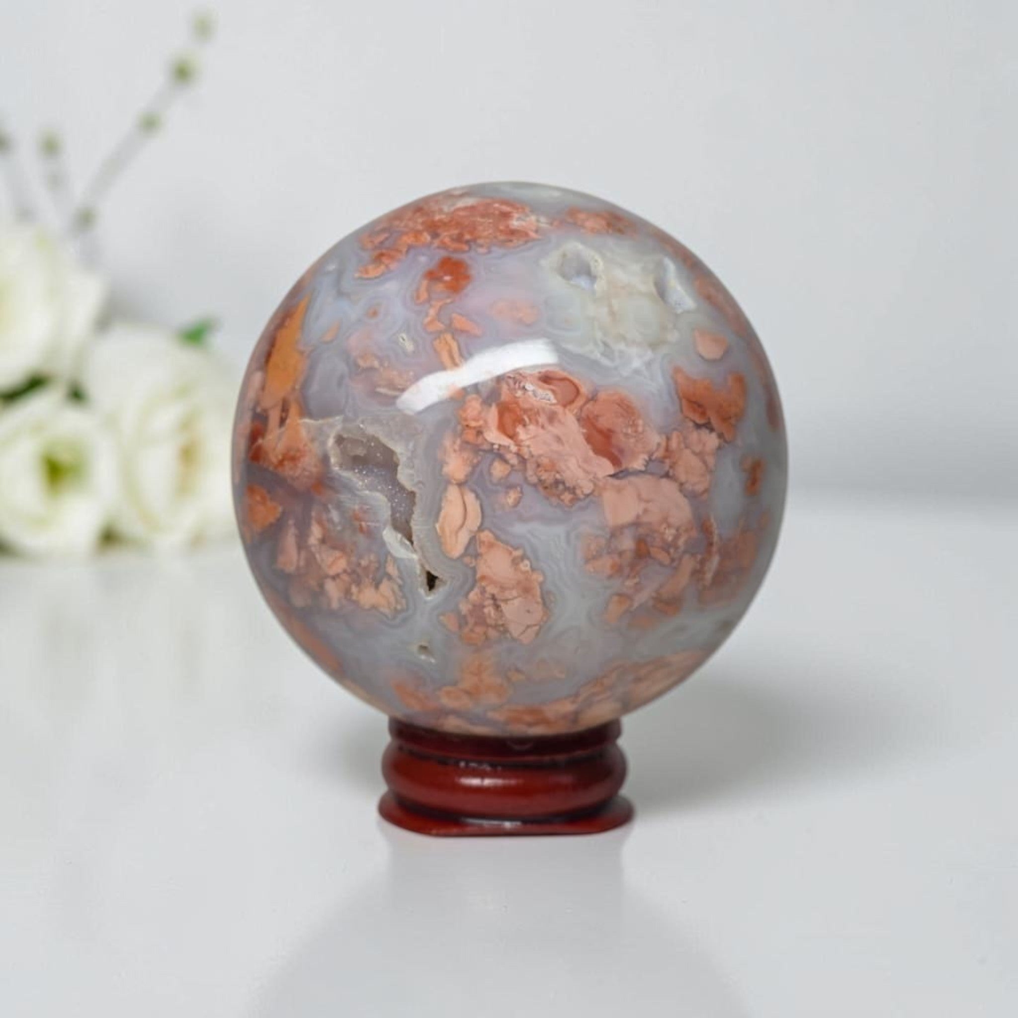 Agate sphere on stand, cloudy blue-gray with orange mineral patches